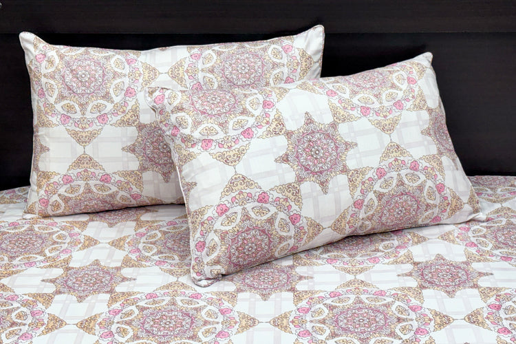 A bed dressed with a white and pink geometric-patterned bedsheet and matching pillows 1.