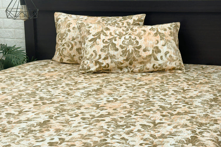 A bed sheet and pillowcases with a floral print in shades of brown displayed on a bed.