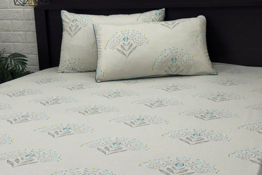 A bed with a custom bed sheet set in shades of grey, yellow, and blue with a floral print design.