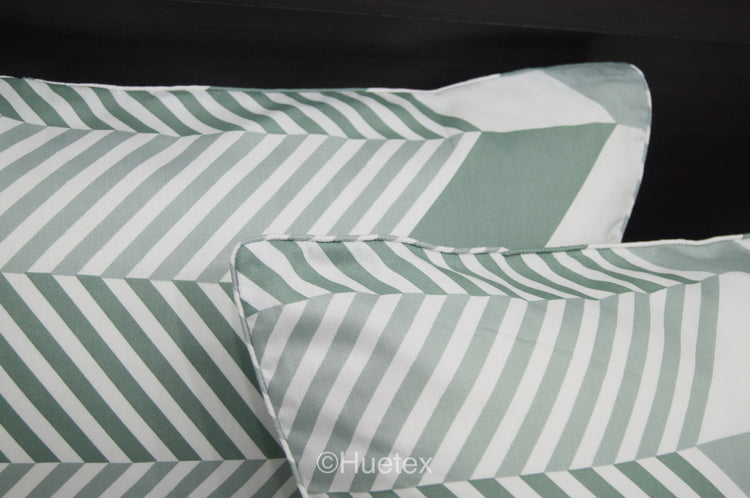 A bed with a geometric patterned aqua pillows.