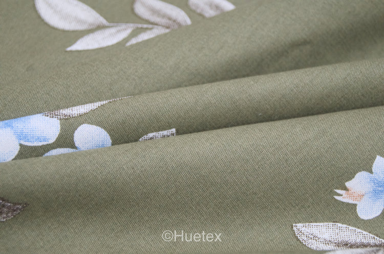 A custom bed sheet with floral geometric print in green folded gently