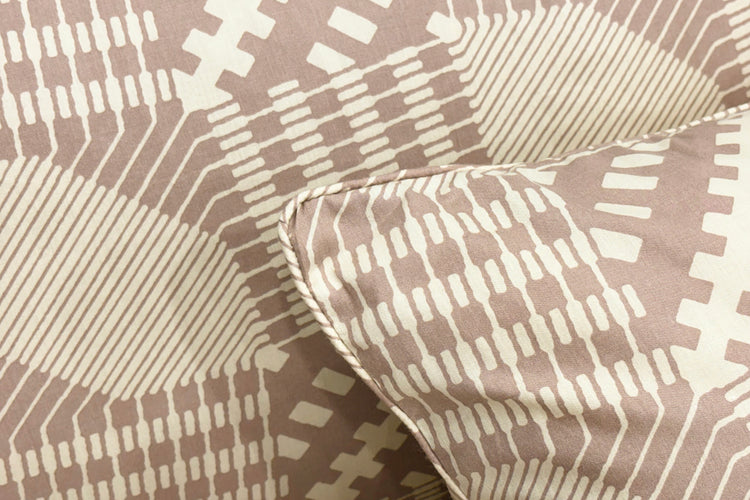 Close-up of a beige pillow with a geometric, circuit-like pattern in white