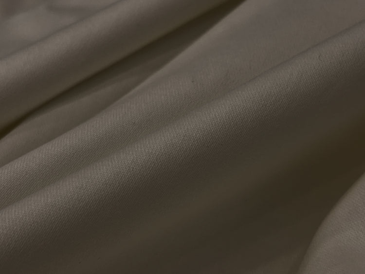 Close-up of smooth, beige fabric with gentle folds and soft texture.