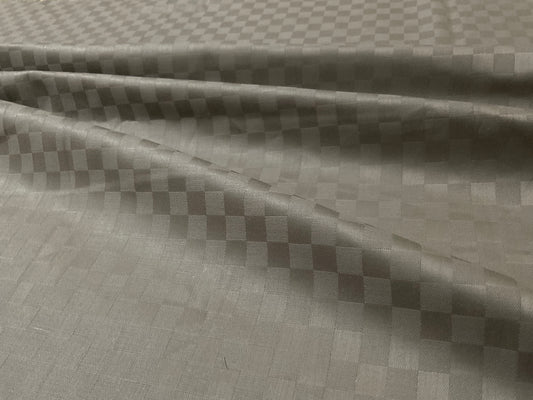 Close-up view of a beige checkered pattern bed sheet fabric .