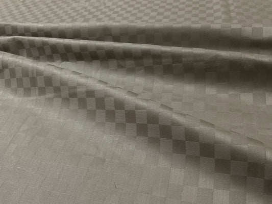 Close-up view of a beige checkered pattern bed sheet fabric .