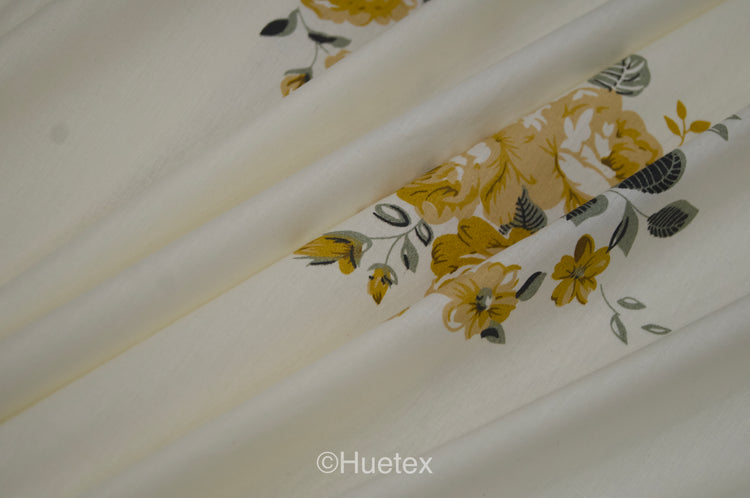 Cream fabric with yellow floral prints draped in soft folds.
