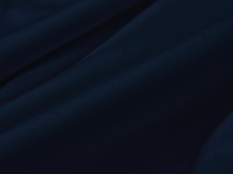 Dark blue fabric draped in soft, flowing folds, creating a sense of depth and texture.