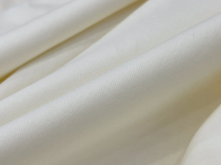 Smooth, cream-colored fabric with soft folds creating a gentle wave pattern.