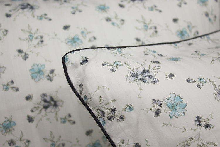 bedsheet and pillow with a floral print design, shades of blue and green .