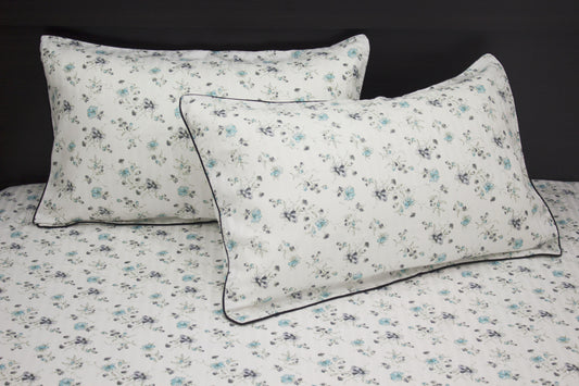 bedsheet and two pillows with a floral print design, shades of blue and green .