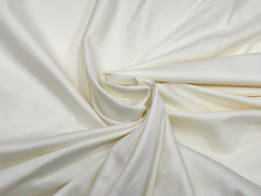 Smooth white silk fabric gracefully draped, forming a gentle spiral at the center.