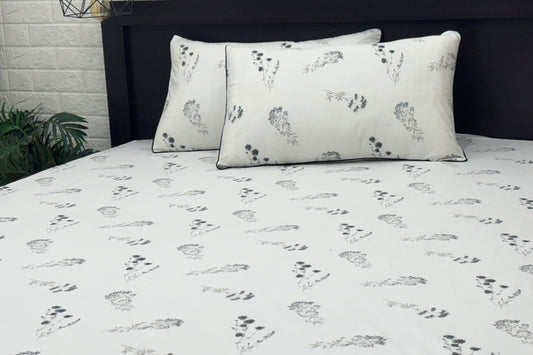 white bed sheets featuring a floral pattern. Two matching pillows .
