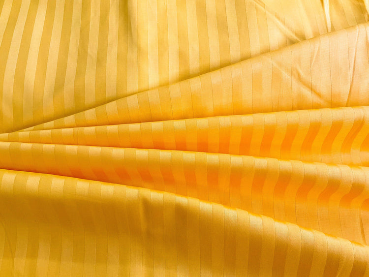 A close-up image of a golden yellow striped sateen bed sheet.
