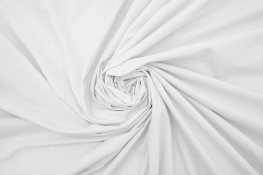 A close-up image of a white, percale weave bed sheet with a focus on texture .