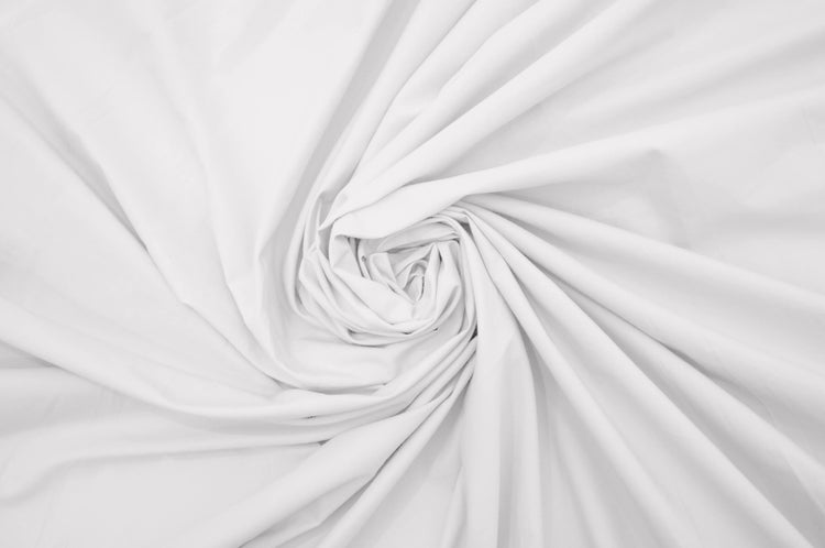 A close-up image of a white, percale weave bed sheet with a focus on texture .