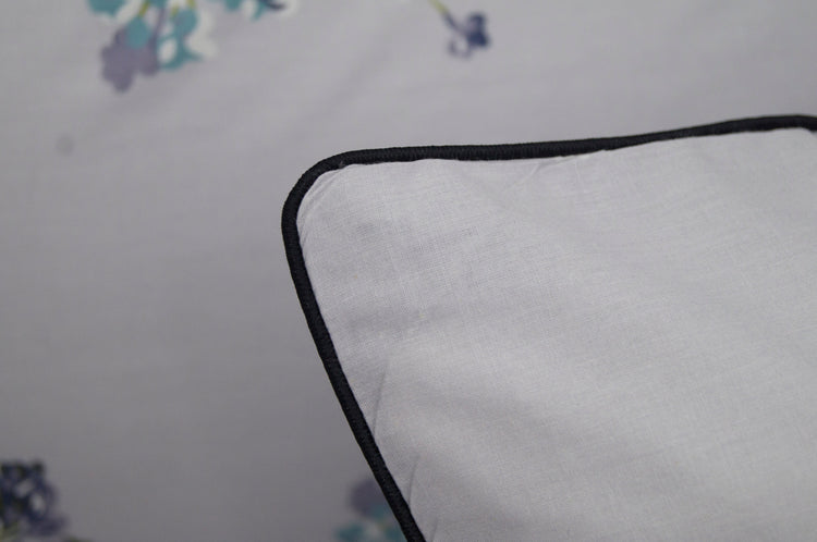 A pillow with a floral print design bedsheet in shades of purple