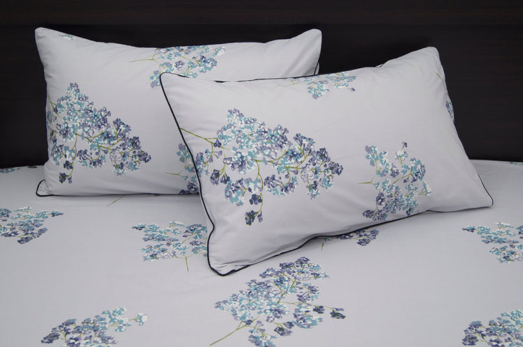 A set of two pillows with a floral print design bedsheet in shades of purple
