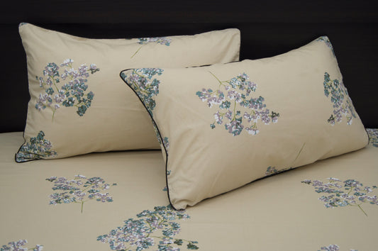 Two beige pillows with floral patterns, featuring small purple and green flowers.