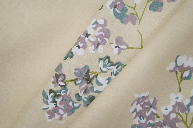 bedsheet with floral patterns, featuring small purple and green flowers.