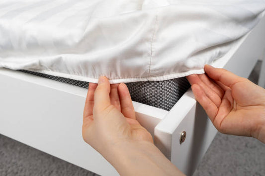  white fitted sheet over a mattress on a white bed frame. 