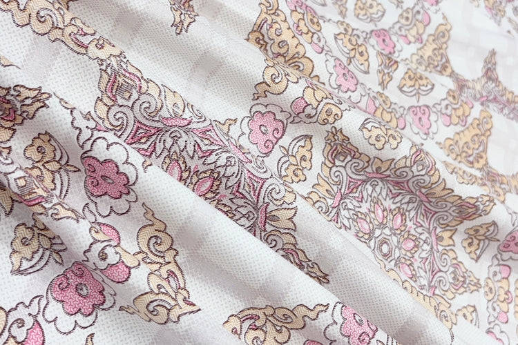 A bed dressed with a white and pink geometric-patterned bedsheet .