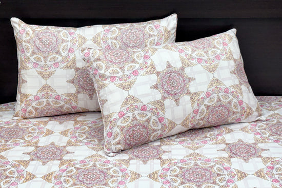 A bed dressed with a white and pink geometric-patterned bedsheet and matching pillows 1.