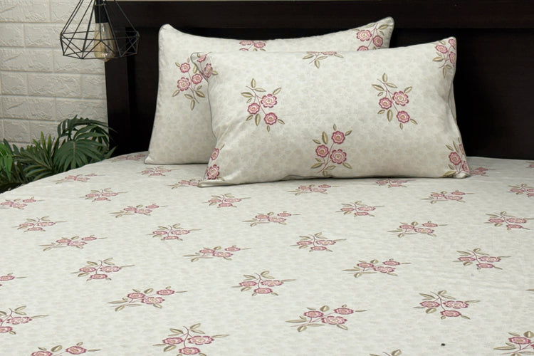 A bed sheet and pillowcases with a floral print design in shades of grey and pink .