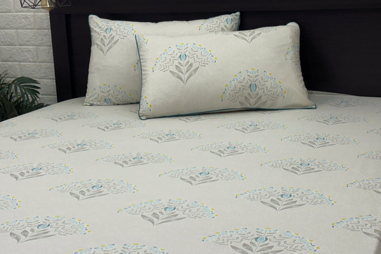 A bed with a custom bed sheet set in shades of grey, yellow, and blue with a floral print design.