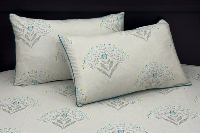 A bed with a custom bed sheet set in shades of grey, yellow, and blue with a floral print design 1.