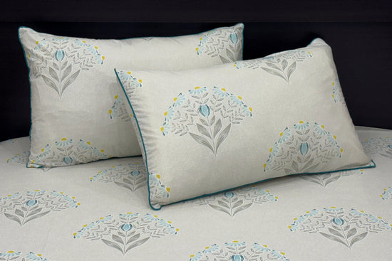 A bed with a custom bed sheet set in shades of grey, yellow, and blue with a floral print design 1.