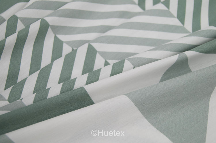 A bed with a geometric patterned aqua bedsheet and gently folded.