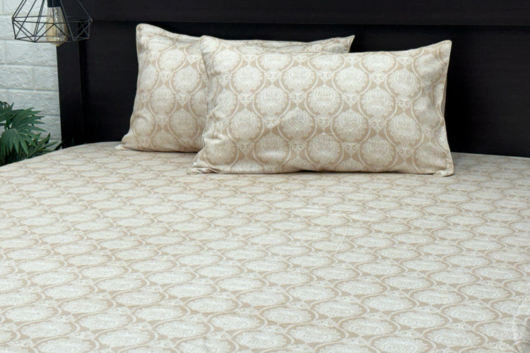 A beige custom bed sheet set with floral print and piping pattern displayed on a bed, including two pillows.