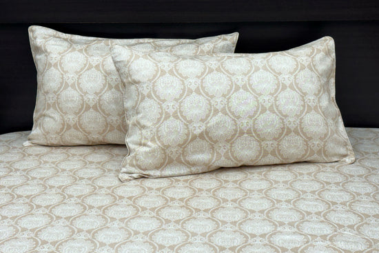 A beige custom bed sheet set with floral print and piping pattern displayed on a bed, including two pillows 1.