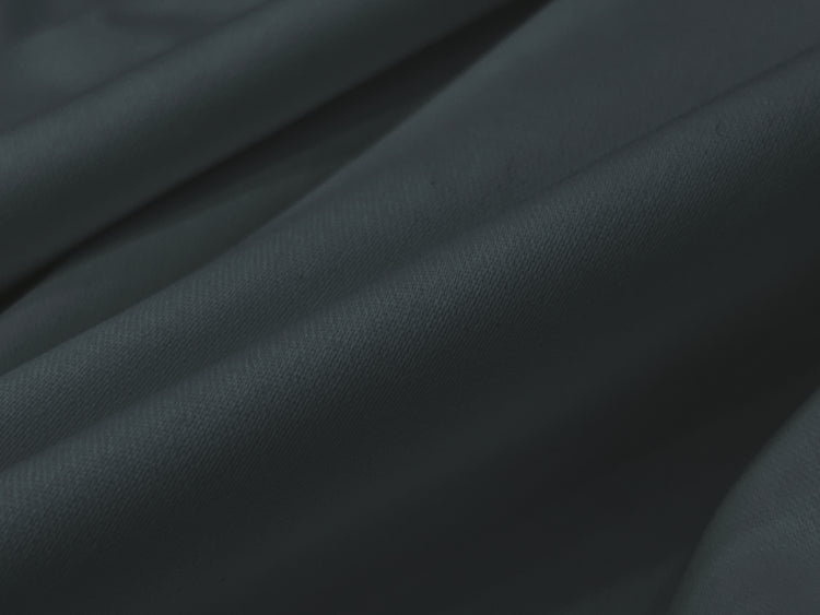 A close-up of dark gray, softly draped fabric bedsheet. 