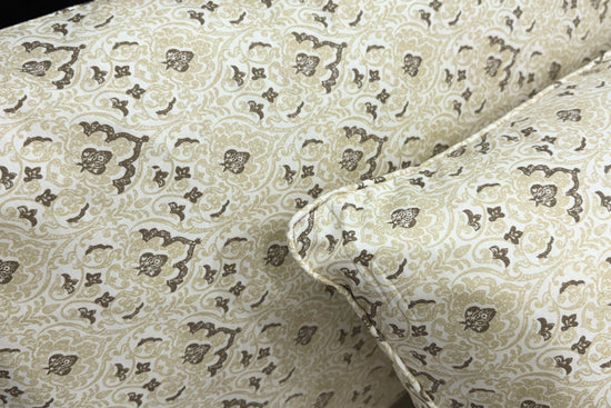 A neatly made bed with a beige floral-patterned pillows .