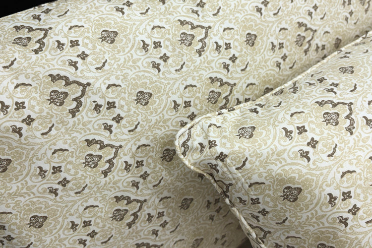 A neatly made bed with a beige floral-patterned pillows .