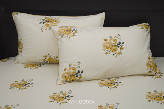 A neatly made bed with a cream sheet and two pillows, all featuring a pattern of yellow and green flowers 2.