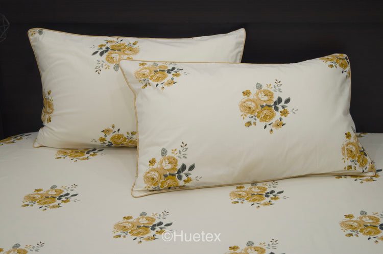 A neatly made bed with a cream sheet and two pillows, all featuring a pattern of yellow and green flowers 2.
