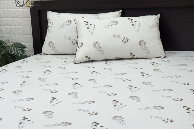 A neatly made bed with a white sheet and two pillows.