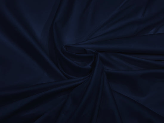 A smooth, dark navy blue fabric neatly folded into elegant, flowing drapery. The texture appears silky.