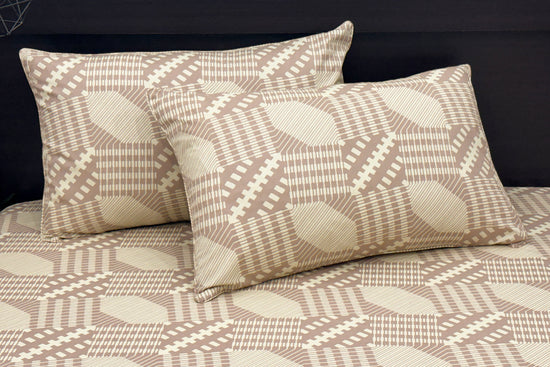 Bed with beige geometric-patterned sheets and two matching pillows 1