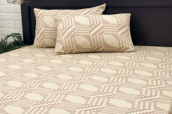 Bed with beige geometric-patterned sheets and two matching pillows 