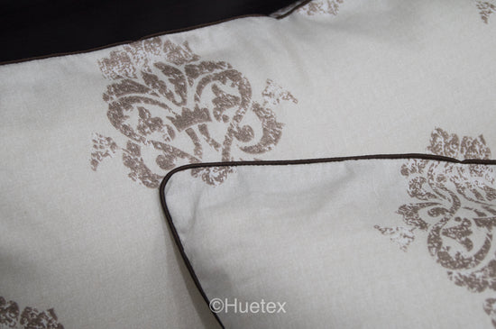 Bed with white and taupe ornate pattern and matching pillow