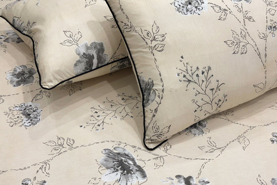 Beige pillow and bedsheet with a delicate gray floral pattern.