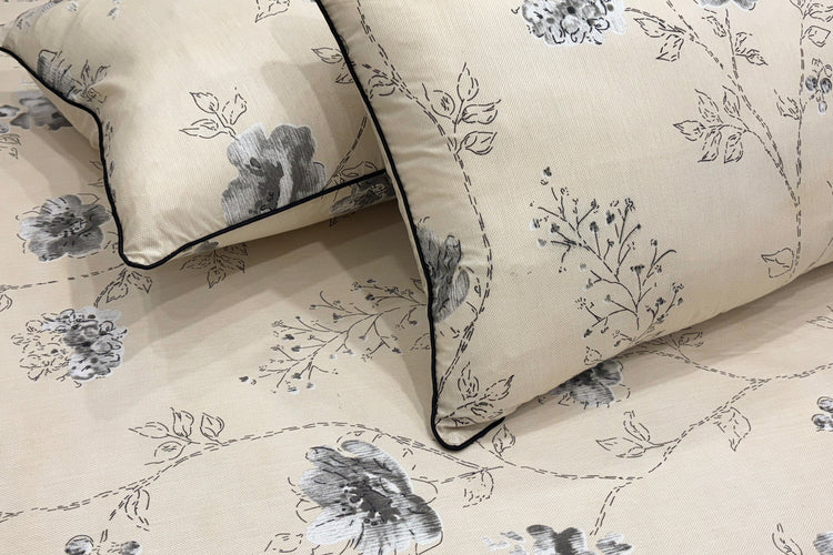Beige pillow and bedsheet with a delicate gray floral pattern.