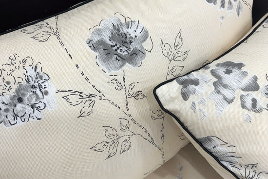 Beige pillow with a delicate gray floral pattern.