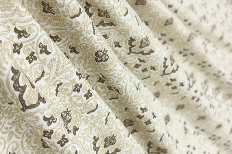 Close-up of beige fabric with intricate brown floral and paisley pattern bedsheet.