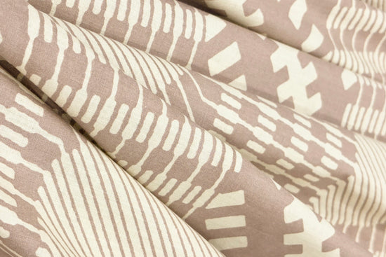 Close-up of folded fabric with geometric patterns in cream and taupe.