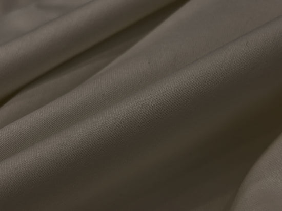 Close-up of smooth, beige fabric with gentle folds and soft texture.