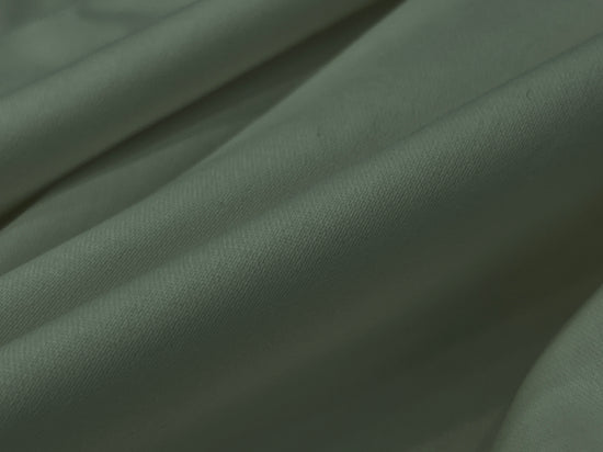 Close-up of soft, light gray fabric with gentle fold bedsheet 